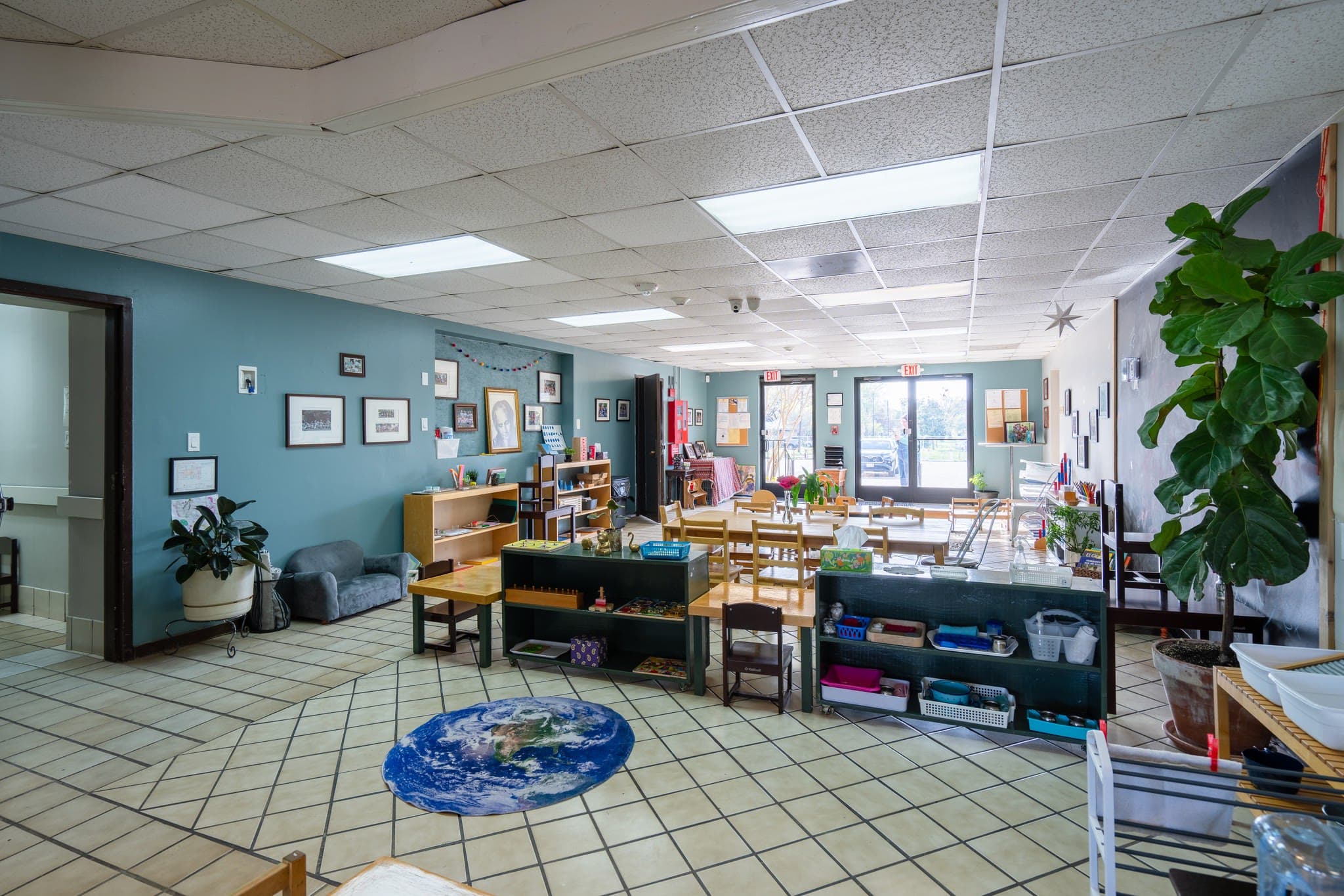 An elementary classroom with soft blue walls, artwork on display, and shelves of materials